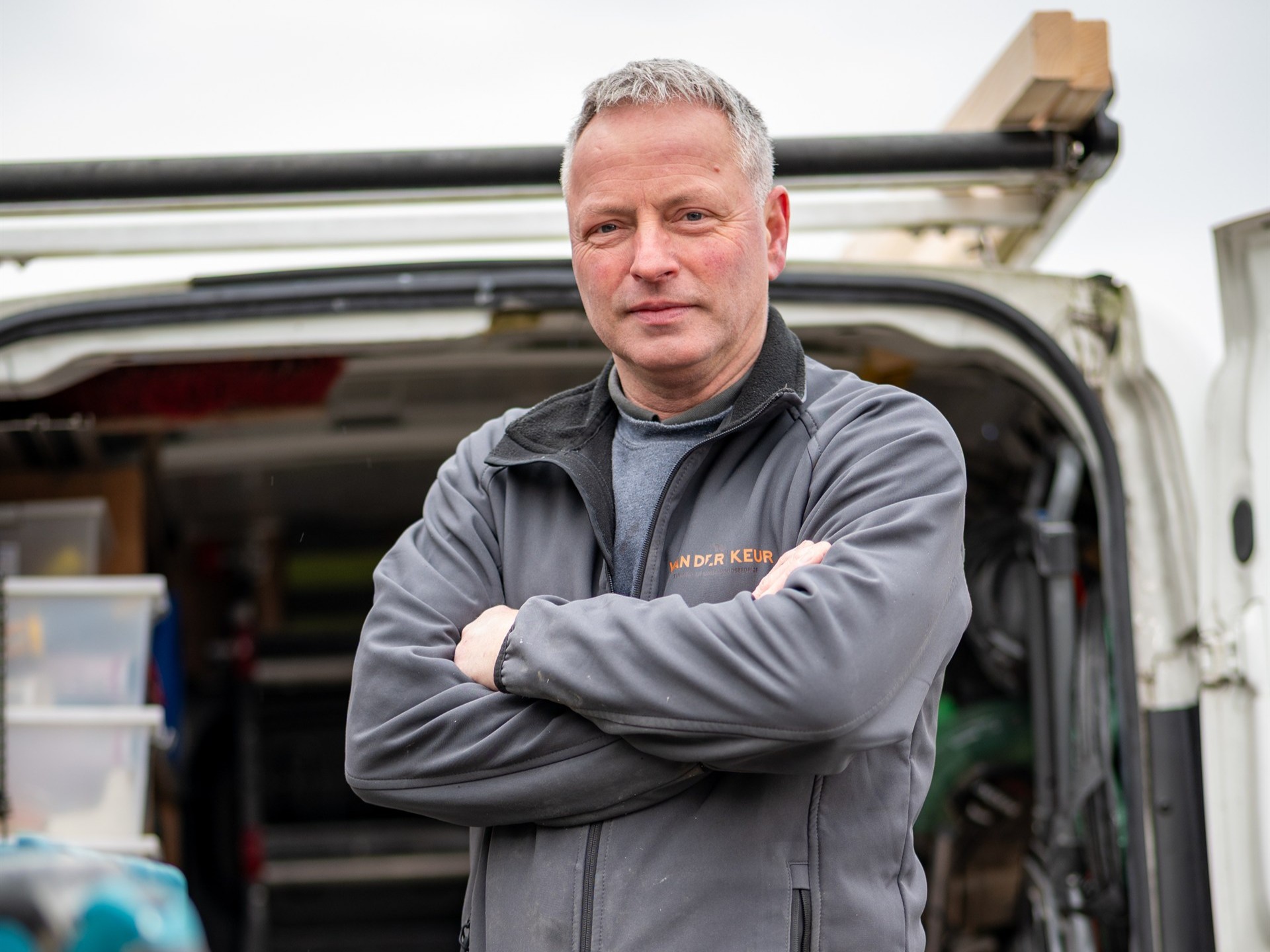 timmerman van Van der Keur bij zijn bedrijfswagen met gereedschap.